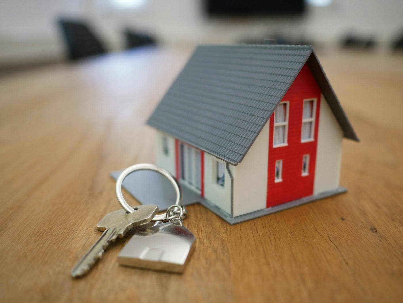A small model house with a set of keys on a wooden table